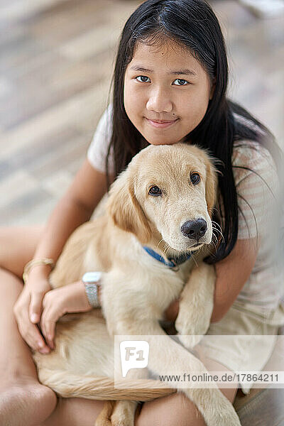 Portrait of a girl with a golden retriever puppy in her embrace