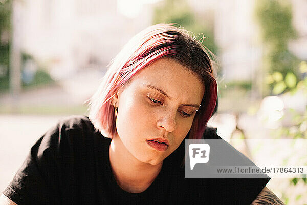 Serious young woman looking in smart phone sitting outdoors