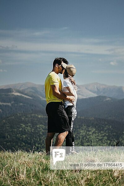 Sporty young couple hugging and kissing on top of the mountains