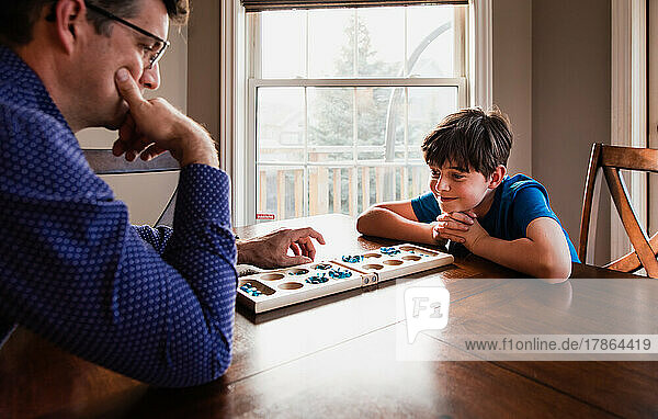 Boy and his father having fun playing a game together at home.