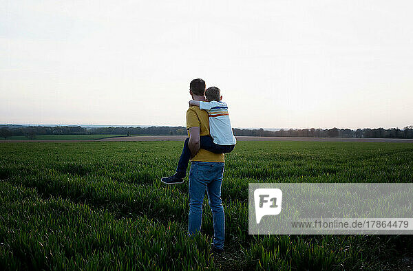 father giving his son a piggyback whilst walking in the countryside