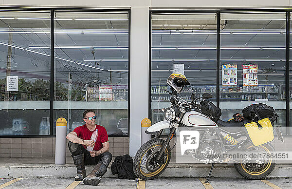 Man taking a break on motorcycle ride in Thailand