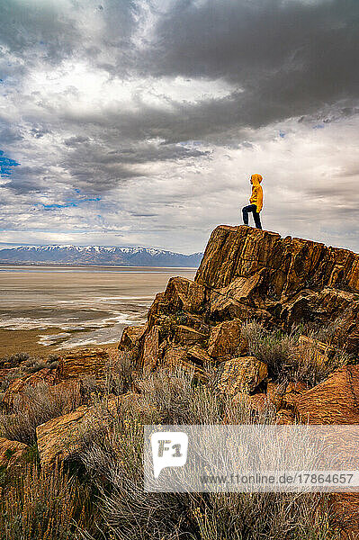 a boy standing on a high rock looking over a dry lake bed in Utah