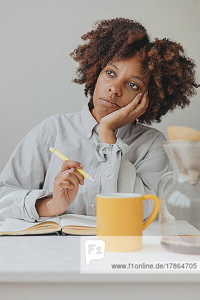 Portrait of a curly thoughtful woman writing a diary.
