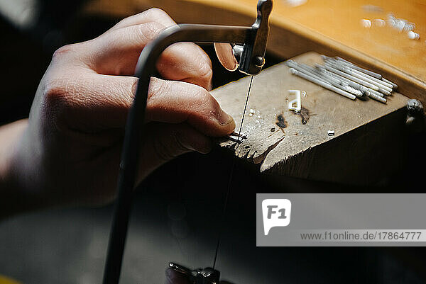 hands of a jeweler working with a file on a blank of silver jewelry