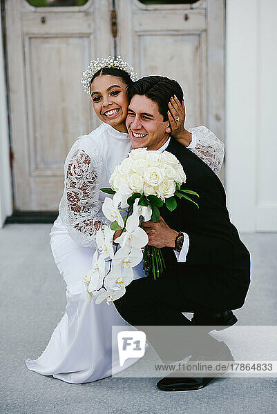 Multiracial bride and groom hug and have big happy smiles