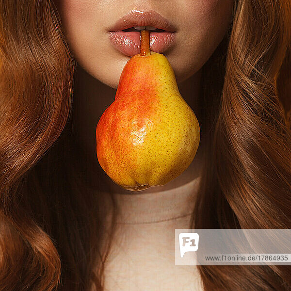 young woman lips holding fresh ripe pear