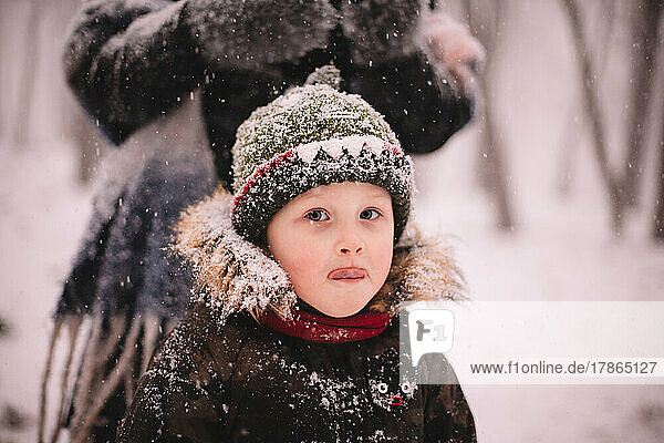Portrait of cute baby boy standing outdoors during snowfall in winter