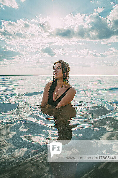 Elegant woman sits in the water. The concept of unity with nature.