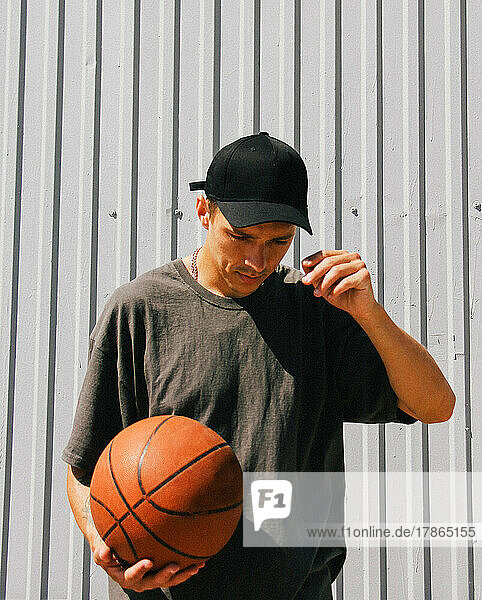 stylish guy in dark clothes and a black cap with a basketball