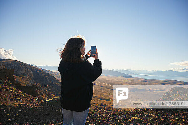 The girl takes pictures on the phone view of the mountain valley