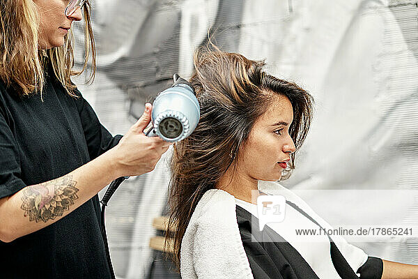 Hairstylist Drying Hair Of Cheerful Customer