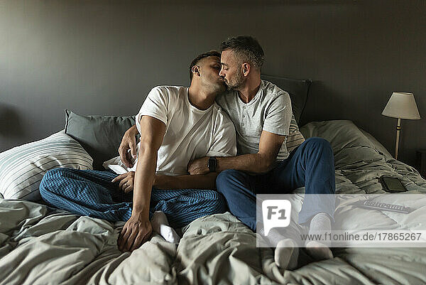 Gay male couple kissing in bed