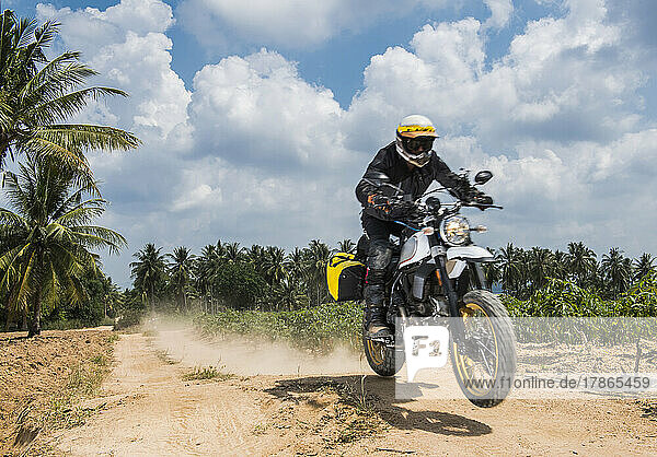 Man riding his scrambler type motorcycle off road in Thailand