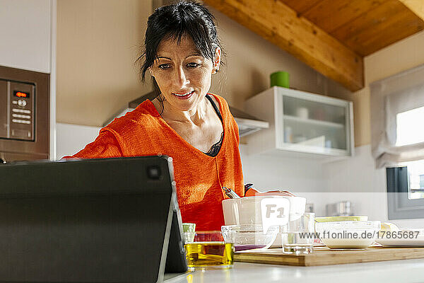 Woman Cooking cake and using the tablet at kitchen