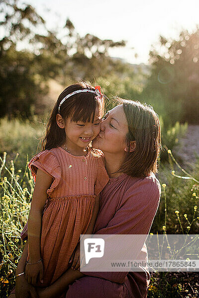 Mom Kissing Daughter at Sunset in Park in San Diego