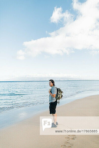 Native American man wearing backpack standing on beach in Maui H