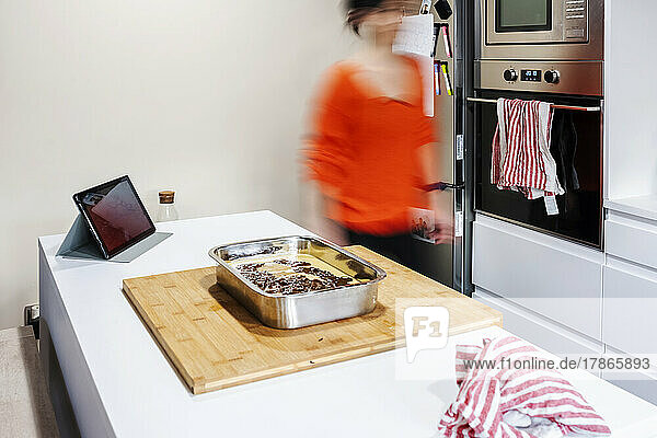 Blurred silhouette of woman walking at kitchen  tray of cake on table