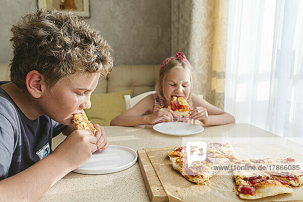 Children eating homemade pizza at home.