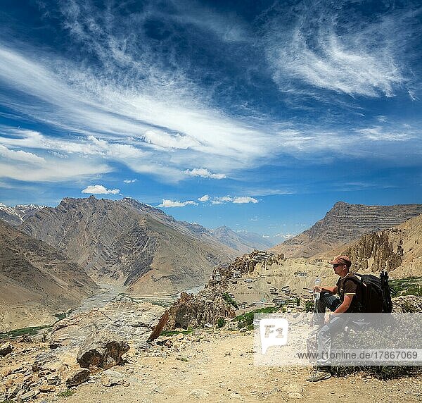 Mountaineer trekker tourist having rest and drinking water in Himalayas mountains  ecotourism concept. Spiti valley. Near Dhankar gompa monastery  Himachal Pradesh  India  Asia