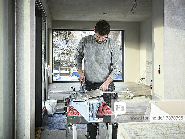 Tiler cutting tiles with equipment at construction site