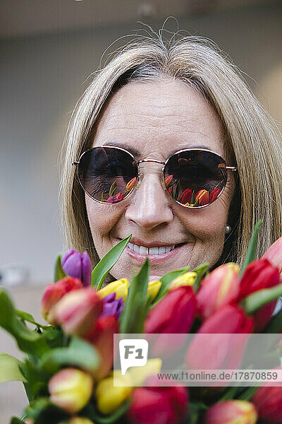 Smiling senior woman with flowers wearing sunglasses