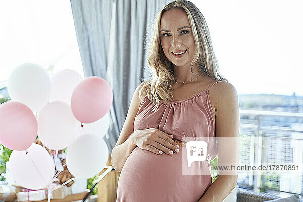Smiling pregnant woman wearing pink dress at baby shower