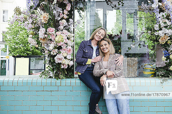 Smiling senior woman embracing daughter outside flower shop