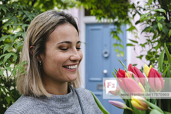 Lächelnde Frau  die Tulpenblumen betrachtet