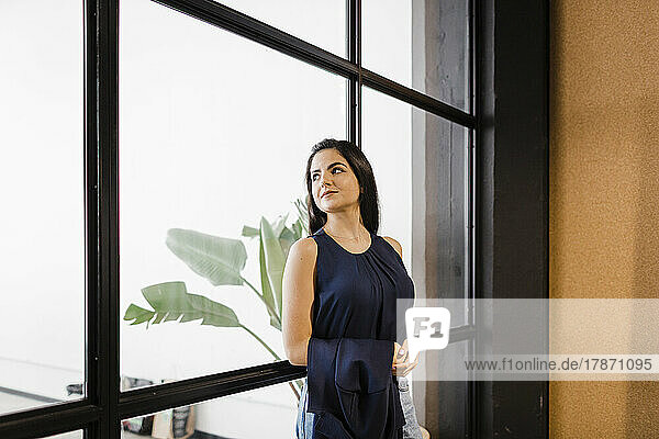 Contemplative businesswoman leaning on glass wall