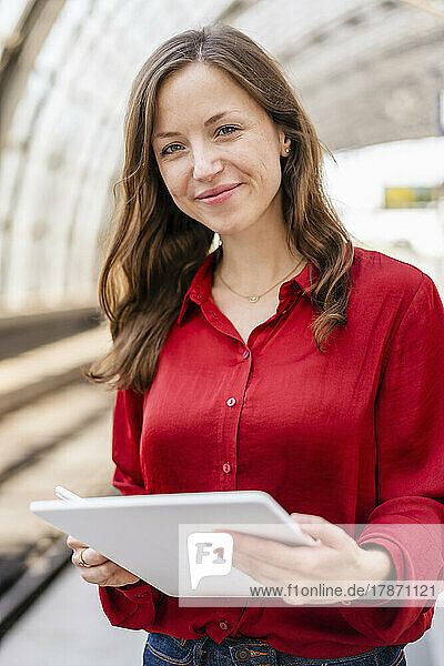 Lächelnde Frau mit braunem Haar  die einen Tablet-PC hält