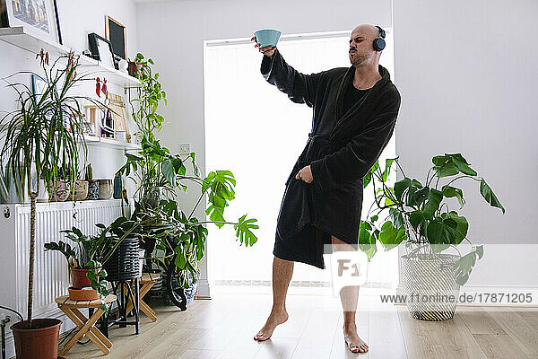 Carefree man wearing wireless headphones enjoying music at home