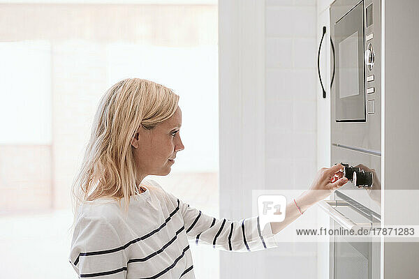 Woman adjusting microwave knobs at home