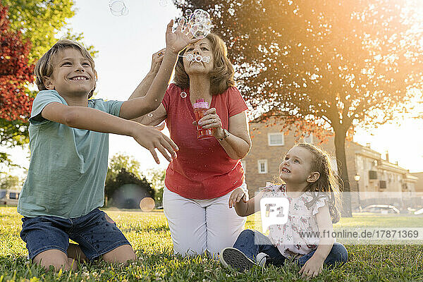 Grandmother blowing bubbles with grandchildren