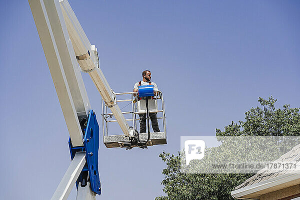Ingenieur steht auf hydraulischer Plattform am Dach