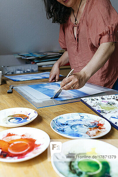 Frau malt zu Hause mit Aquarell auf Papier
