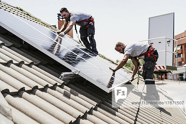 Technicians installing solar panels on rooftop