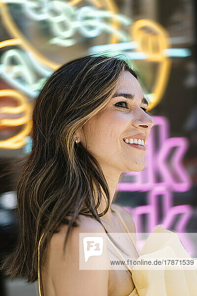Happy young woman in front of neon lights