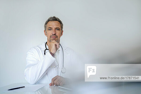 Portrait of mature doctor sitting at desk in medical practice