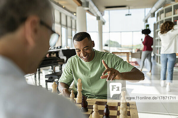 Happy businessman playing chess with colleague in office