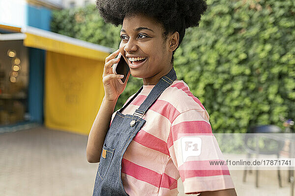 Glückliche Frau mit Afro-Frisur  die auf dem Smartphone spricht