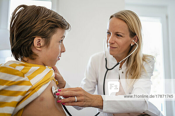 Female doctor with stethoscope examining boy