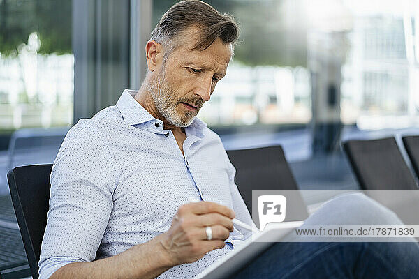 Mature businessman using graphic tablet sitting on seat