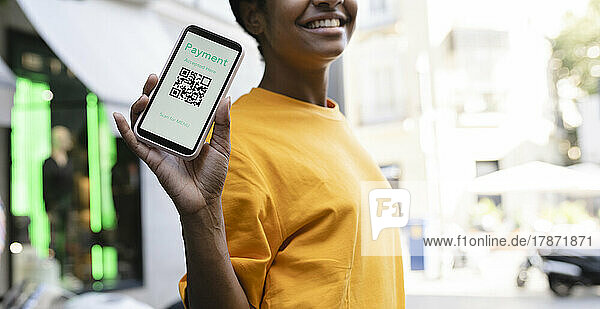 Smiling woman showing smart phone with QR code