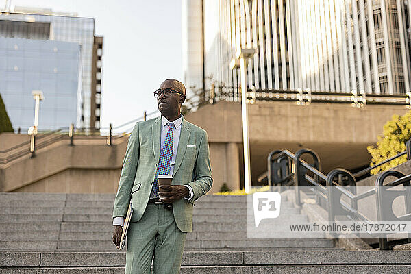 Mature businessman with laptop and coffee cup on steps