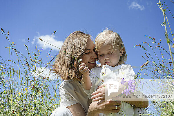 Lächelnde Mutter umarmt süße Tochter auf dem Feld