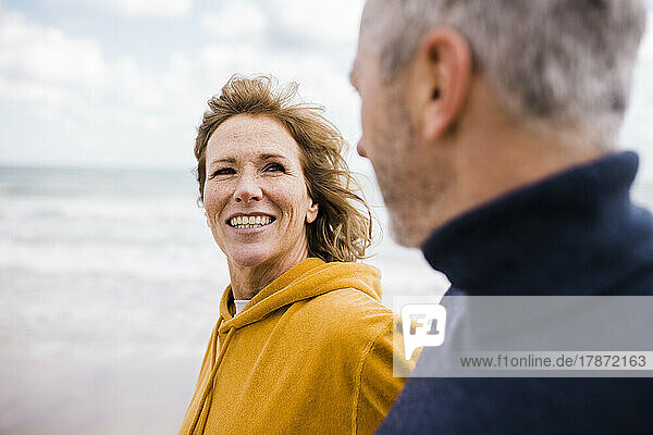 Glückliche reife Frau mit Mann  der am Strand spaziert