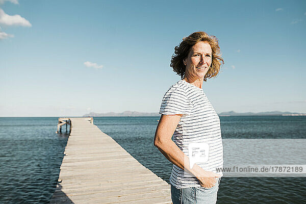 Happy mature woman standing on jetty