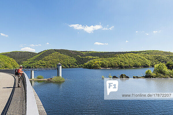 Senior man standing by railing looking at lake on sunny day  Eifel National Park  Germany