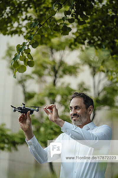 Smiling mature businessman analyzing drone